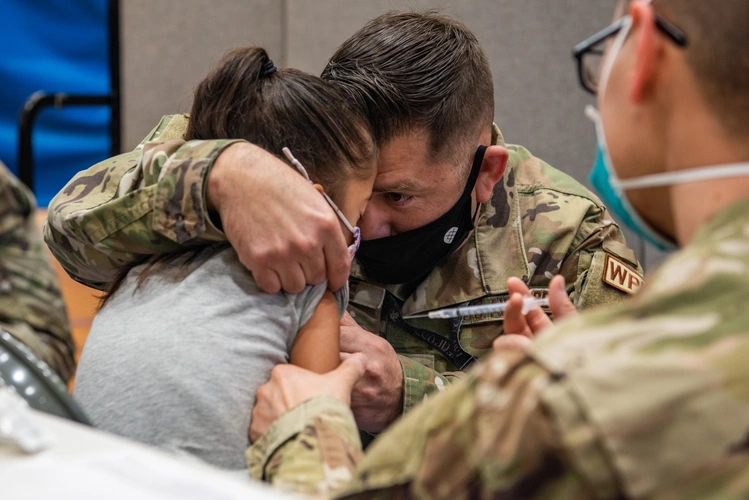 Soldier consoling a child getting a shot